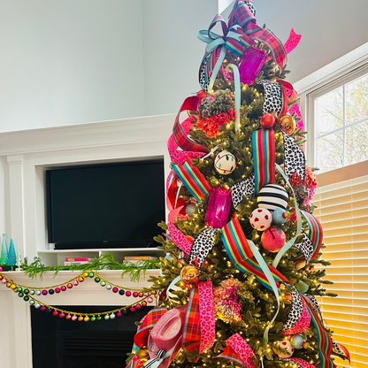 Decorated Christmas tree with colorful ribbons and ornaments in a living room.