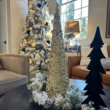 Decorative Christmas trees in a living room setting with a couch and lamp.