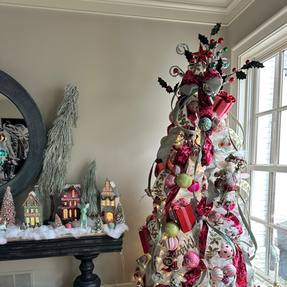 Decorative Christmas tree with colorful ornaments and lights in a room with a fireplace and window.