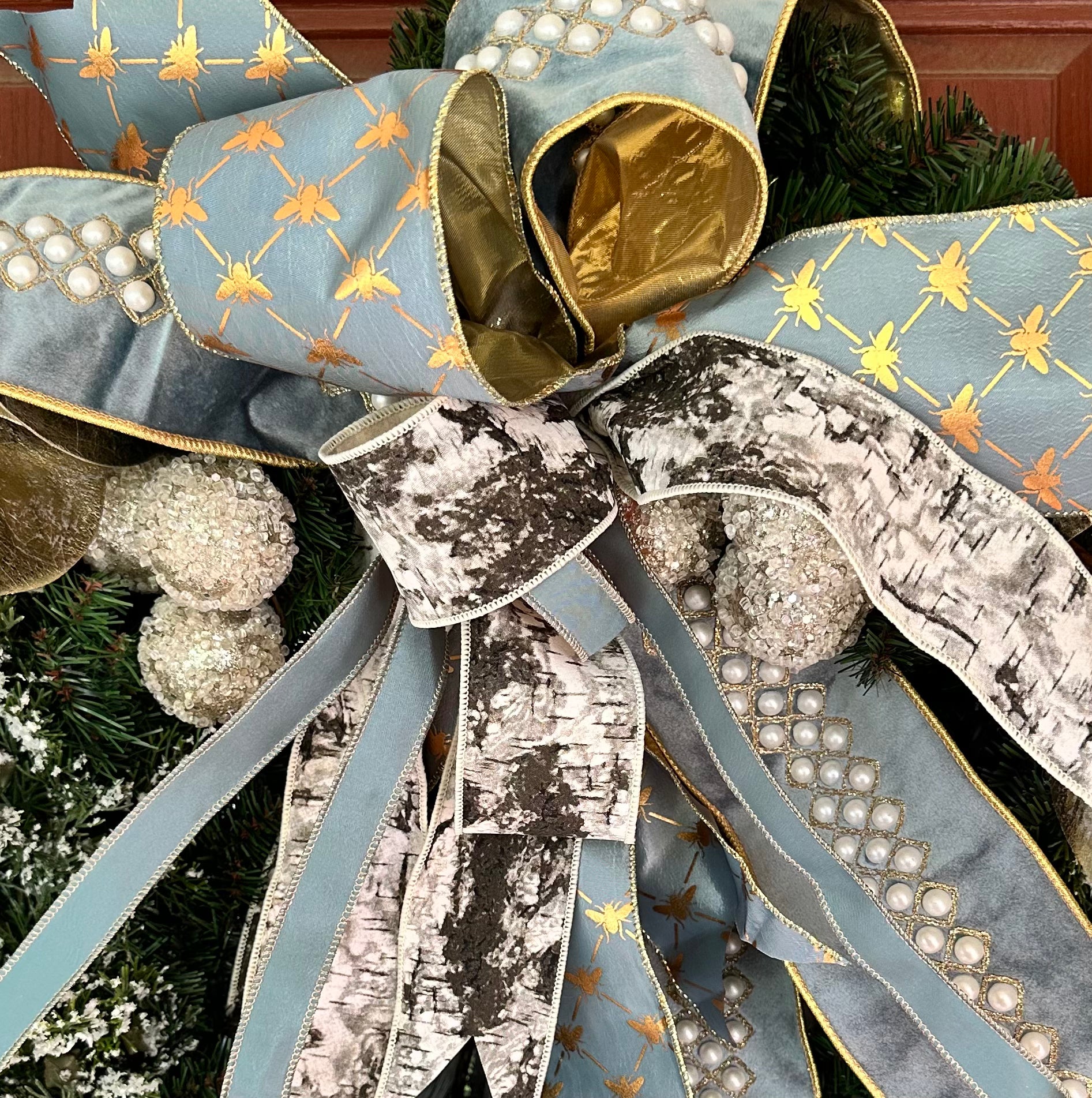 Decorative bow with blue, gold, and silver ribbons on a Christmas tree.