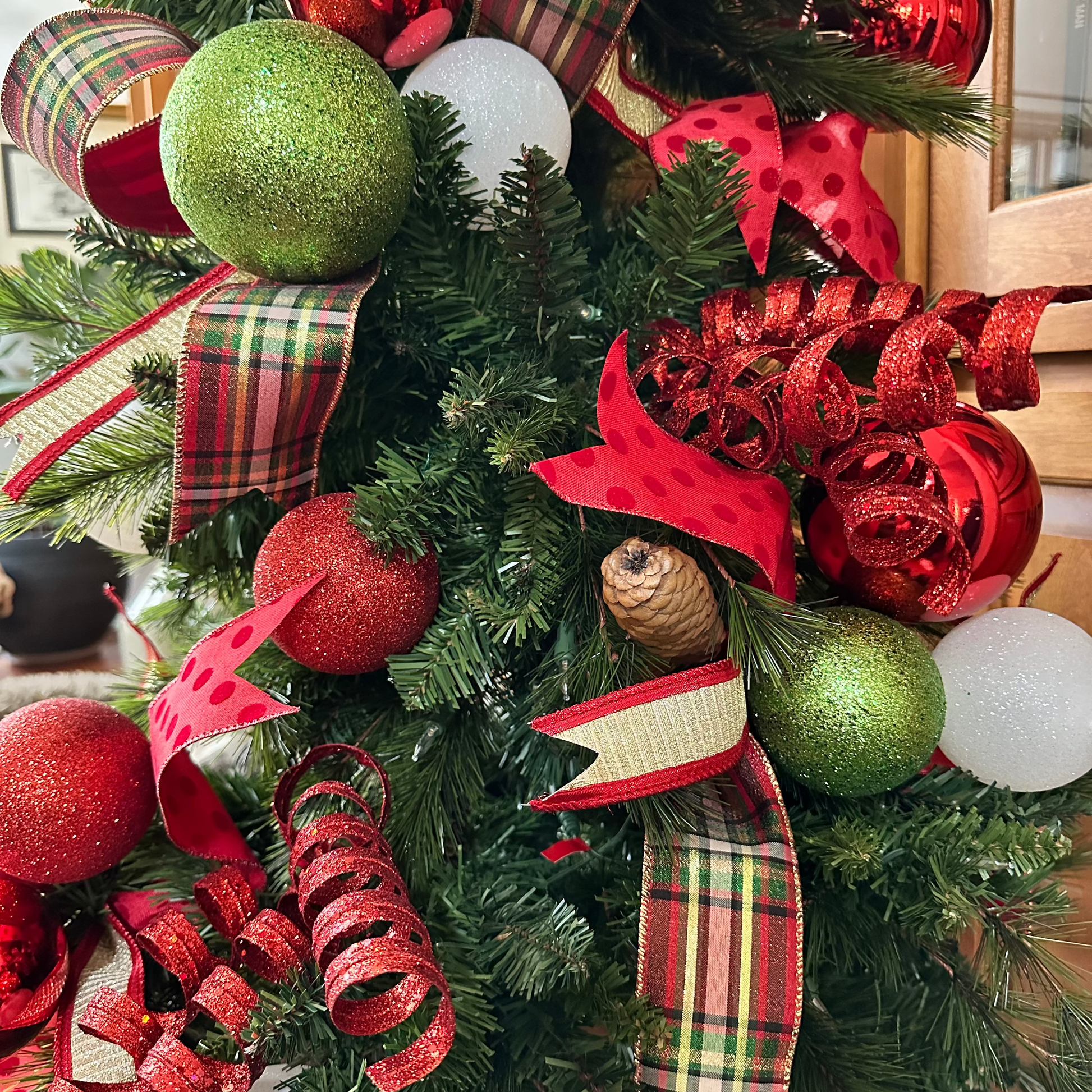 Decorative Christmas wreath with red, green, and plaid ribbons.