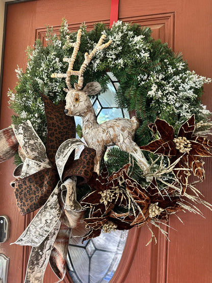 Decorative wreath with a deer figure and leopard print ribbon on a door.