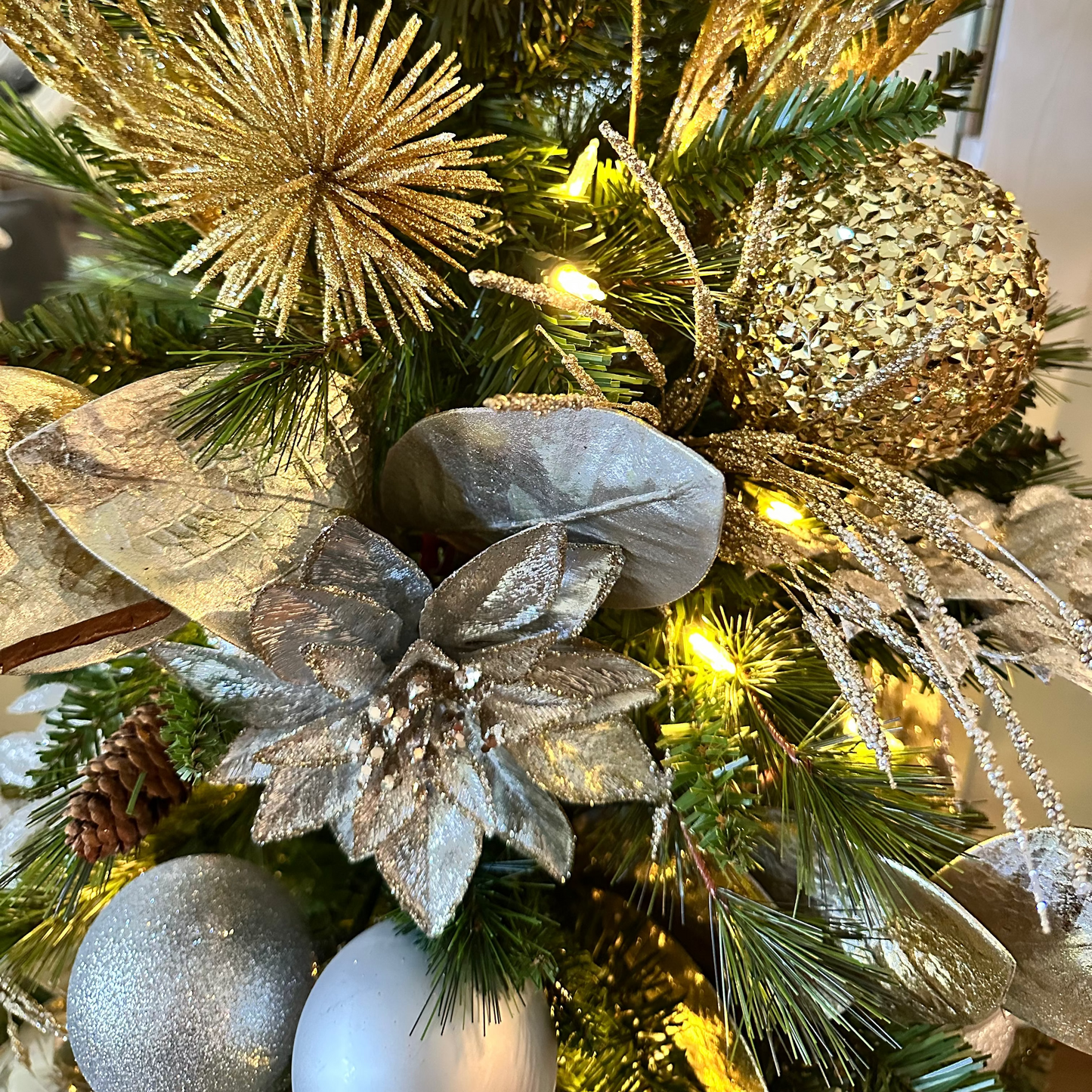 Decorative Christmas tree with gold, silver, and green ornaments.